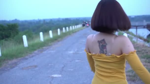 屋外でポーズをとる黄色のドレスの美しいアジアの女性 — ストック動画