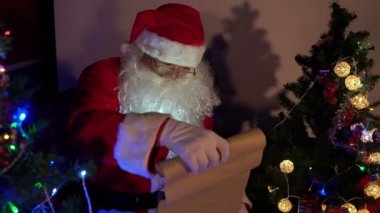 Noel Baba, Noel ağacının yanında çelenkli mektup okuyor. Mutlu tatiller.