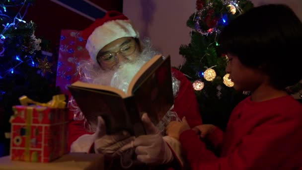 Книга Санта Клауса Маленьким Мальчиком Возле Елки Гирляндой Концепция Счастливого — стоковое видео