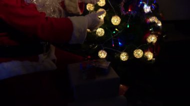 Noel Baba 'nın Noel ağacını çelenkle süslemesi, mutlu bayramlar.