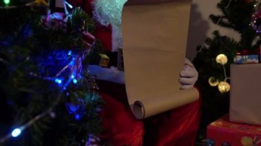 Noel Baba, Noel ağacının yanında çelenkli mektup okuyor. Mutlu tatiller.
