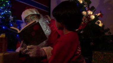 Noel Baba Noel ağacının yanında çelenk okuyan çocuk, mutlu bayramlar.