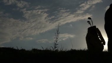Güzel günbatımında golf oynayan Asyalı golfçünün silueti