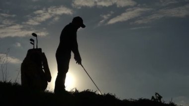 Güzel günbatımında golf oynayan Asyalı golfçünün silueti