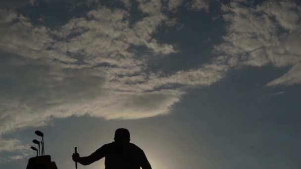 美しい夕日の中でゴルフをするアジアのゴルファーのシルエット — ストック動画