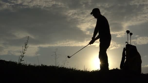 美しい夕日の中でゴルフをするアジアのゴルファーのシルエット — ストック動画