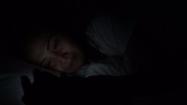 アジアの女性は夜にベッドでスマートフォンを再生します タイの人々 — ストック動画