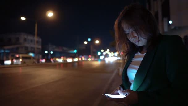 Wanita Asia Menggunakan Smartphone Saat Berdiri Pinggir Jalan Pada Malam — Stok Video