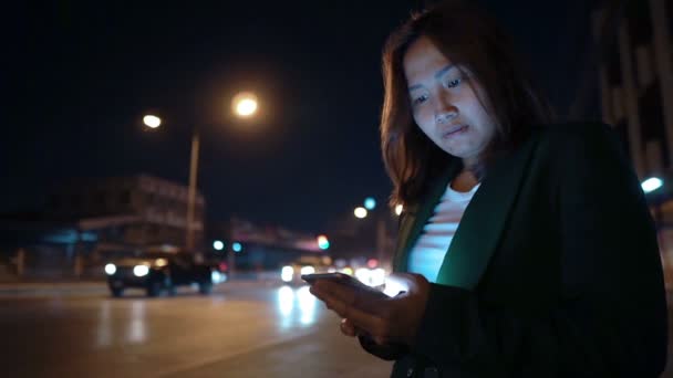 Wanita Asia Menggunakan Smartphone Saat Berdiri Pinggir Jalan Pada Malam — Stok Video