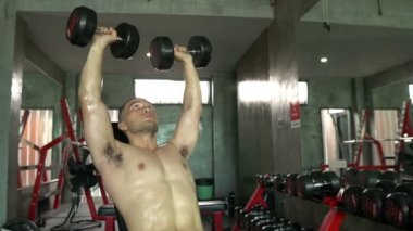 Büyük kaslı Asyalı adam spor salonunda ağırlık çalışması yapıyor.