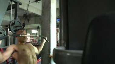 Büyük kaslı Asyalı adam spor salonunda ağırlık çalışması yapıyor.