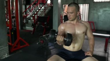 Büyük kaslı Asyalı adam spor salonunda ağırlık çalışması yapıyor.