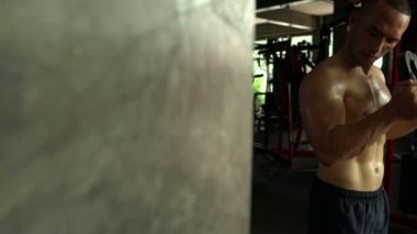 Büyük kaslı Asyalı adam spor salonunda ağırlık çalışması yapıyor.