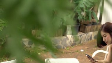 Avluda dizüstü bilgisayarda çalışan genç Asyalı kadın, ev konseptinde çalışıyor. 