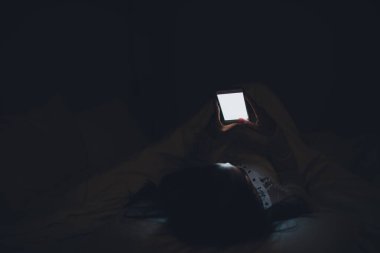Asyalı kadın gece yatakta akıllı telefonla oyun oynuyor, Taylandlılar, sosyal medya bağımlısı.