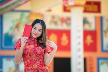 Cheongsam elbiseli güzel Asyalı kadın portresi, Tayland halkı, mutlu Çin yeni yılı konsepti, kırmızı zarf..