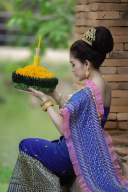 Tayland elbisesi giymiş güzel Asyalı bir kadının portresi geleneksel dua Kratong 'u loy kratong festivaline katılması için tutuyor.