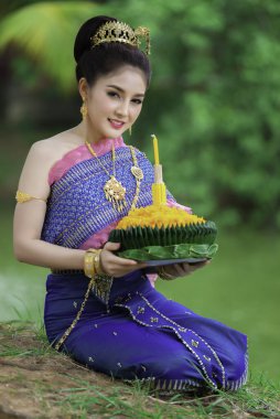 Tayland elbisesi giymiş güzel Asyalı bir kadının portresi geleneksel dua Kratong 'u loy kratong festivaline katılması için tutuyor.