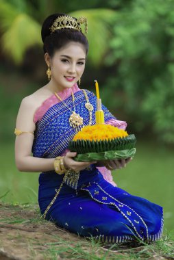 Tayland elbisesi giymiş güzel Asyalı bir kadının portresi geleneksel dua Kratong 'u loy kratong festivaline katılması için tutuyor.