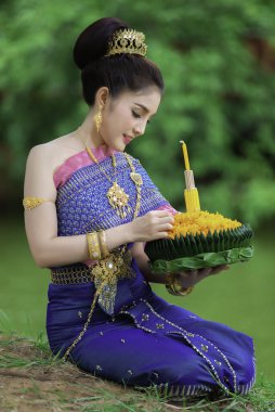 Tayland elbisesi giymiş güzel Asyalı bir kadının portresi geleneksel dua Kratong 'u loy kratong festivaline katılması için tutuyor.