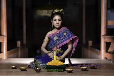 Tayland elbisesi giymiş güzel Asyalı bir kadının portresi geleneksel dua Kratong 'u loy kratong festivaline katılması için tutuyor.