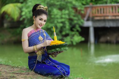 Tayland elbisesi giymiş güzel Asyalı bir kadının portresi geleneksel dua Kratong 'u loy kratong festivaline katılması için tutuyor.
