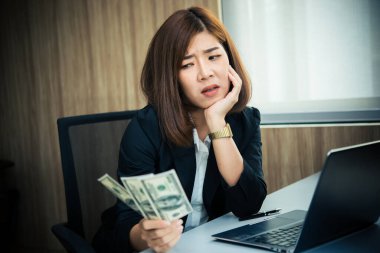 Ofiste çalışan Asyalı bir kadın, iş yoğunluğundan dolayı stresli olan genç bir iş kadını. Masasında bir sürü dosya var. Tayland halkı maaşı hakkında çok fazla düşünüyor..