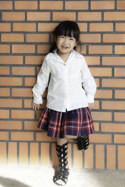 Küçük bir kızın portresi. Duvarda fotoğraf çektirmek için.