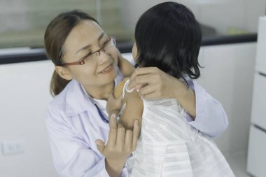 Asyalı doktor steteskop kullanarak nefes alıp verişini ve kalbini kontrol ediyor.