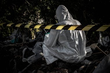 Asyalı bilim adamı tehlikeli bölgede çalışan tehlikeli kimyasalları kontrol etmek için kimya koruması giyiyor.