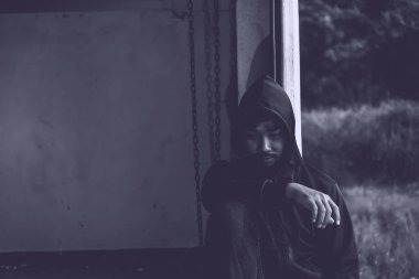 Üzgün Asyalı bağımlı dışarıda oturuyor.