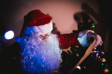 Noel Baba 'nın portresi çocuklara hediye göndermek için kağıt okumak ve liste adı kontrol etmek