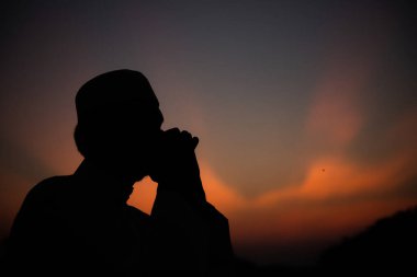 Siluet Genç Asyalı Müslüman adam gün batımında dua ediyor, Ramazan festivali konsepti