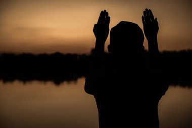 Günbatımında dua eden Asyalı genç Müslüman adamın silueti, Ramazan festivali konsepti