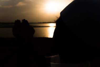 Günbatımında dua eden Asyalı genç Müslüman adamın silueti, Ramazan festivali konsepti