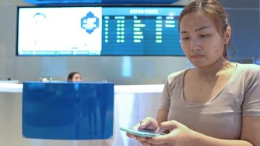 Havaalanında cep telefonu kullanan Asyalı kadın.
