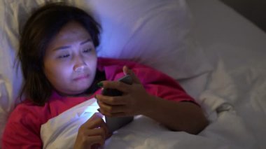 Asyalı kadın gece yatakta akıllı telefon çalar.
