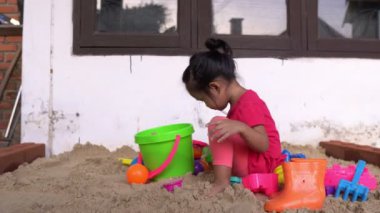 Küçük kız ön tarafta kum oynuyor, dinlenme zamanı.