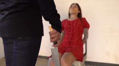 Kadın fidyeci elinde bıçak ve iple bağlanmış Asyalı rehine kadını tehdit ediyor. 