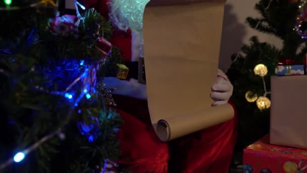 サンタ節の肖像は紙を読み リスト名をチェックして子供に贈り物を送る — ストック動画