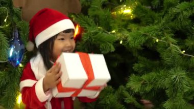 Noel ağacının yanında Noel Baba şapkası takan sevimli Asyalı küçük kız portresi