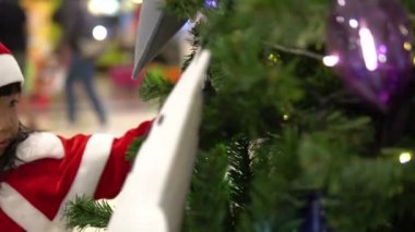 Noel ağacının yanında Noel Baba şapkası takan sevimli Asyalı küçük kız portresi