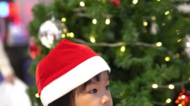 Noel ağacının yanında Noel Baba şapkası takan sevimli Asyalı küçük kız portresi