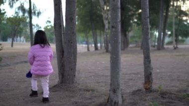 Küçük Asyalı kızın portresi park ormanında kışlık kıyafetler giyer.