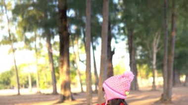 Küçük Asyalı kızın portresi park ormanında kışlık kıyafetler giyer.