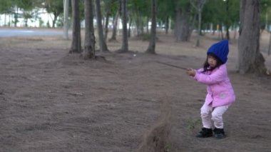 Küçük Asyalı kızın portresi park ormanında kışlık kıyafetler giyer.