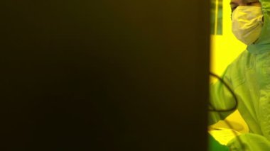 Laboratuvarda çalışan koruyucu toz kıyafeti giyen bilim adamları