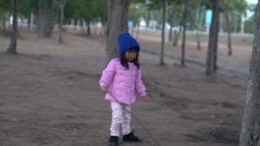 Küçük Asyalı kızın portresi park ormanında kışlık kıyafetler giyer.