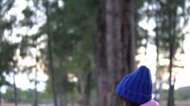 Küçük Asyalı kızın portresi park ormanında kışlık kıyafetler giyer.