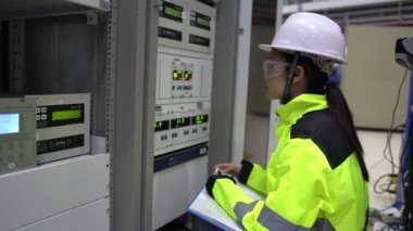 Elektrik mühendisi kadın kontrol odasındaki elektrik dağıtım kabinesinde voltajı kontrol ediyor.